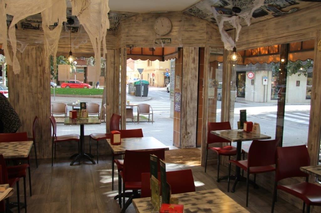 Imagen de interior del bar cafetería con mesa alta, mesas bajas y sillas