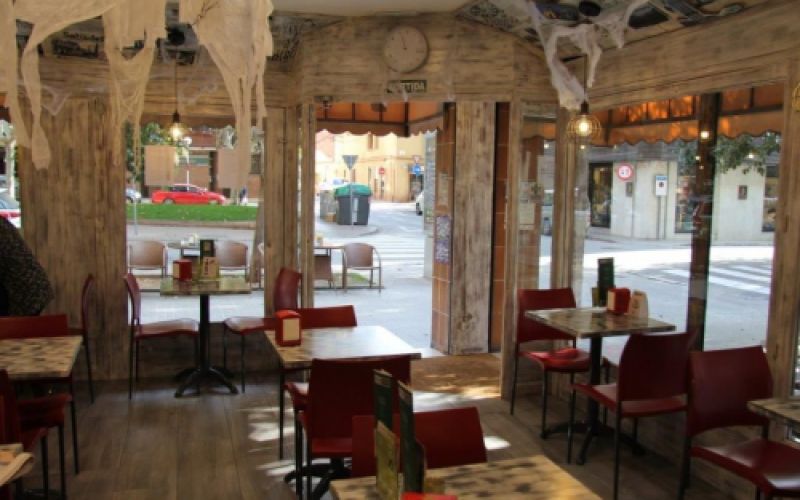 Imatge interior del bar cafeteria amb taula alta, taules baixes i cadires